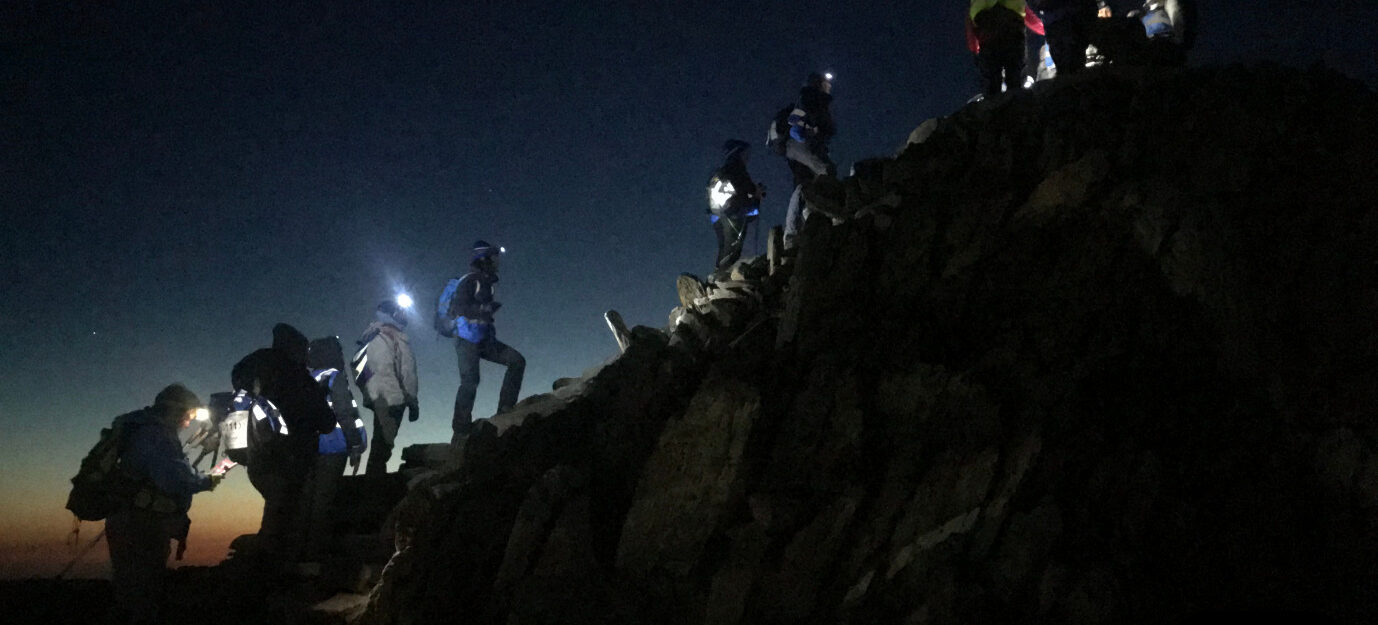 A group of hikers climbing mount Snowdon at night time with torches