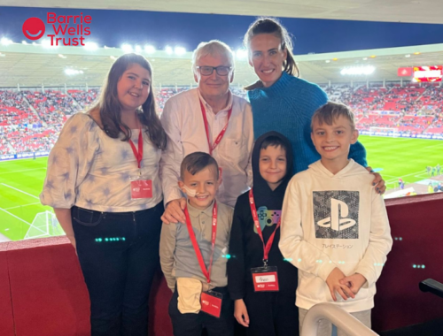 A family with three children stand in a VIP box at a football stadium