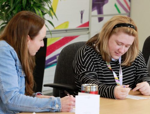 A staff member supporting an intern at a desk in an office