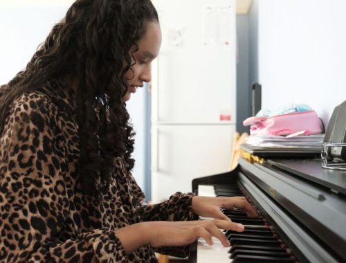 A blind girl with long curly hair playing the piano
