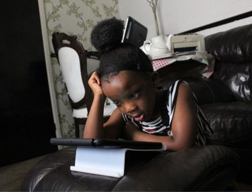 A little girl using a tablet on the sofa