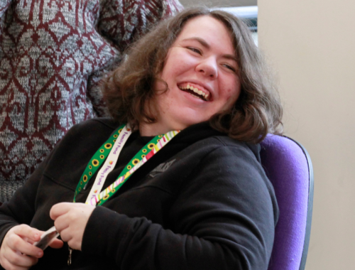 a young person with a sunflower lanyard laughing in the office