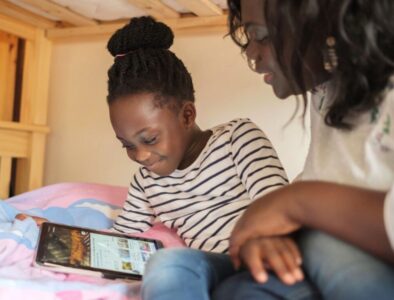 Mother and daughter looking at a tablet device on a bottom bunk