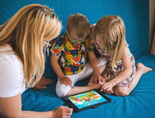 A mum with son and daughter sitting on a sofa looking at a tablet