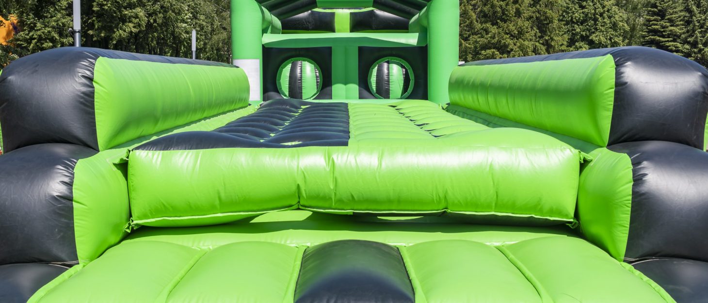 A large green inflatable challenge course outside in a field