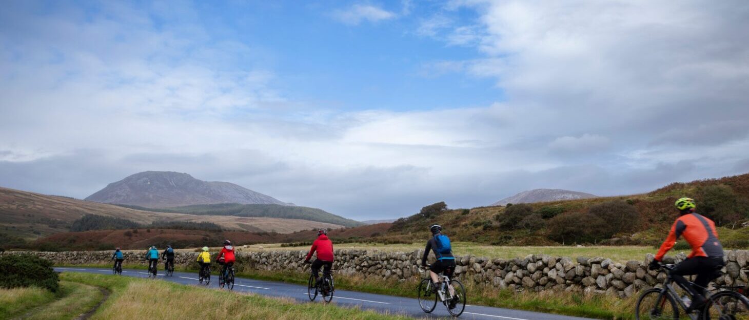 Cyclists on country route with hills in the distance and blue sky