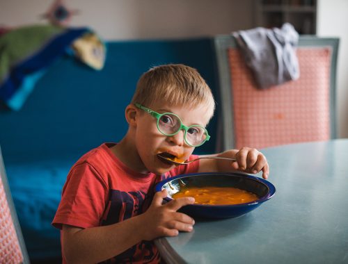 A child eating soup while looking at the camera