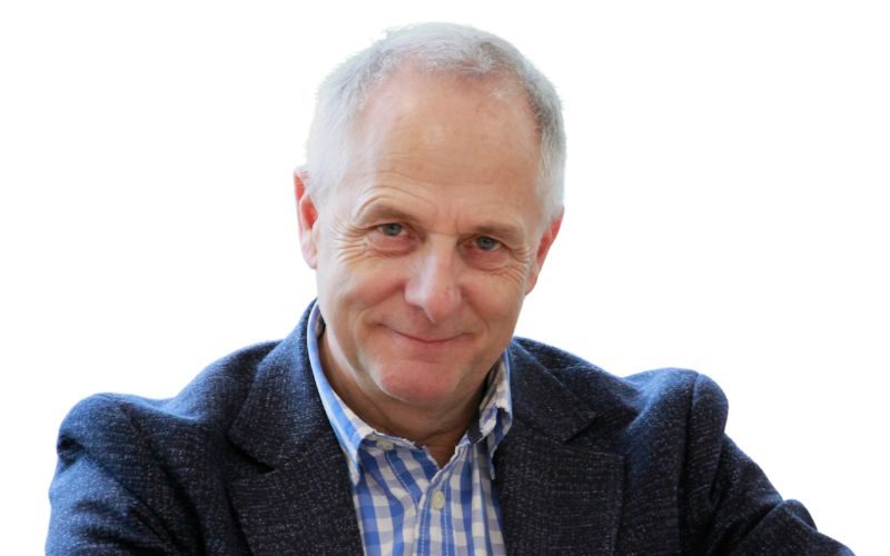 A man wearing a blue and white checked shirt and a speckled navy blazer