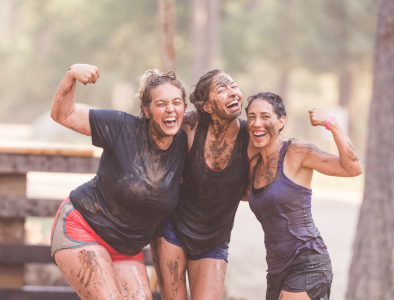 Three girls hugging after finishing a mud race