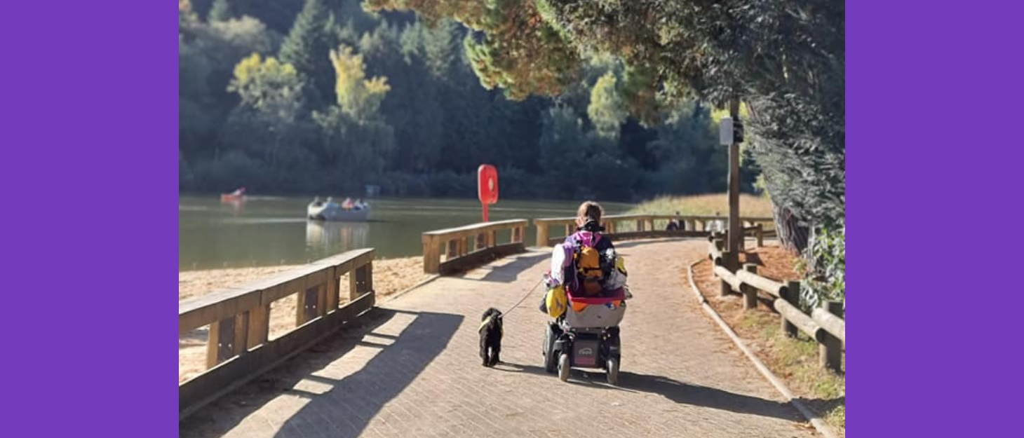 Girl in wheelchair travelling towards beach with her assistance dog next to her
