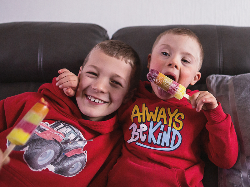 two brothers in red jumpers on the sofa eating popsicles
