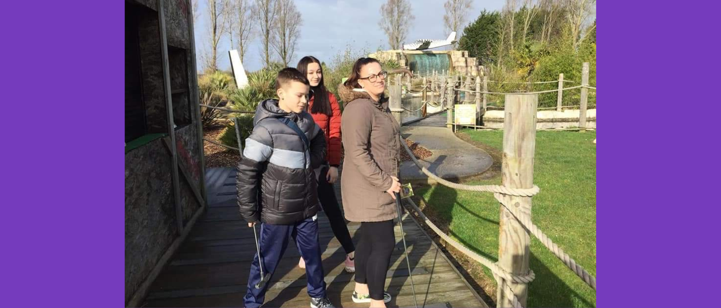 Mum with her two children going round a mini golf course