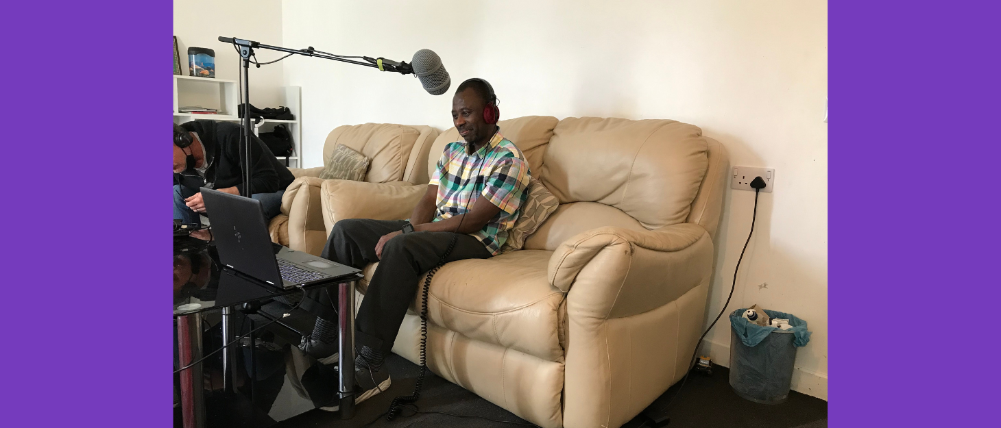 Man sits on sofa in living room doing podcast recording with headphones and microphone