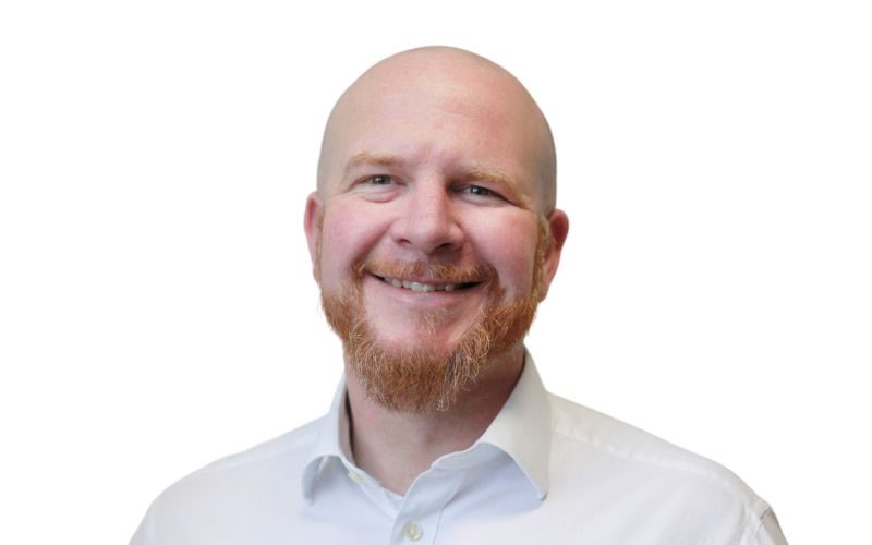 A man wearing a white shirt with a short ginger beard