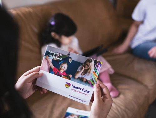 someone looking at a family fund booklet while a child is playing in the background