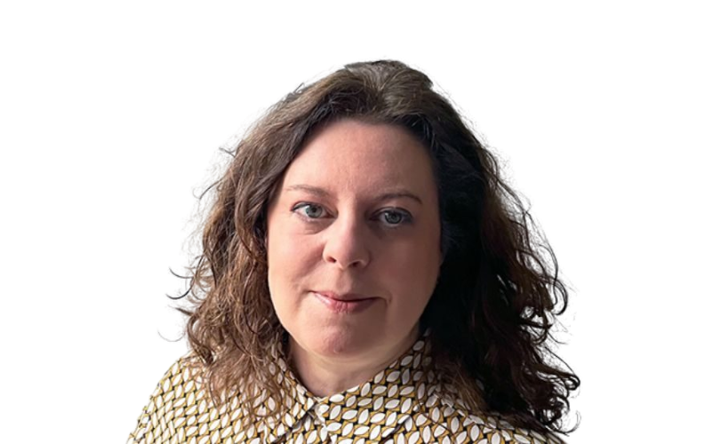 A woman wearing a blouse with dark curly hair