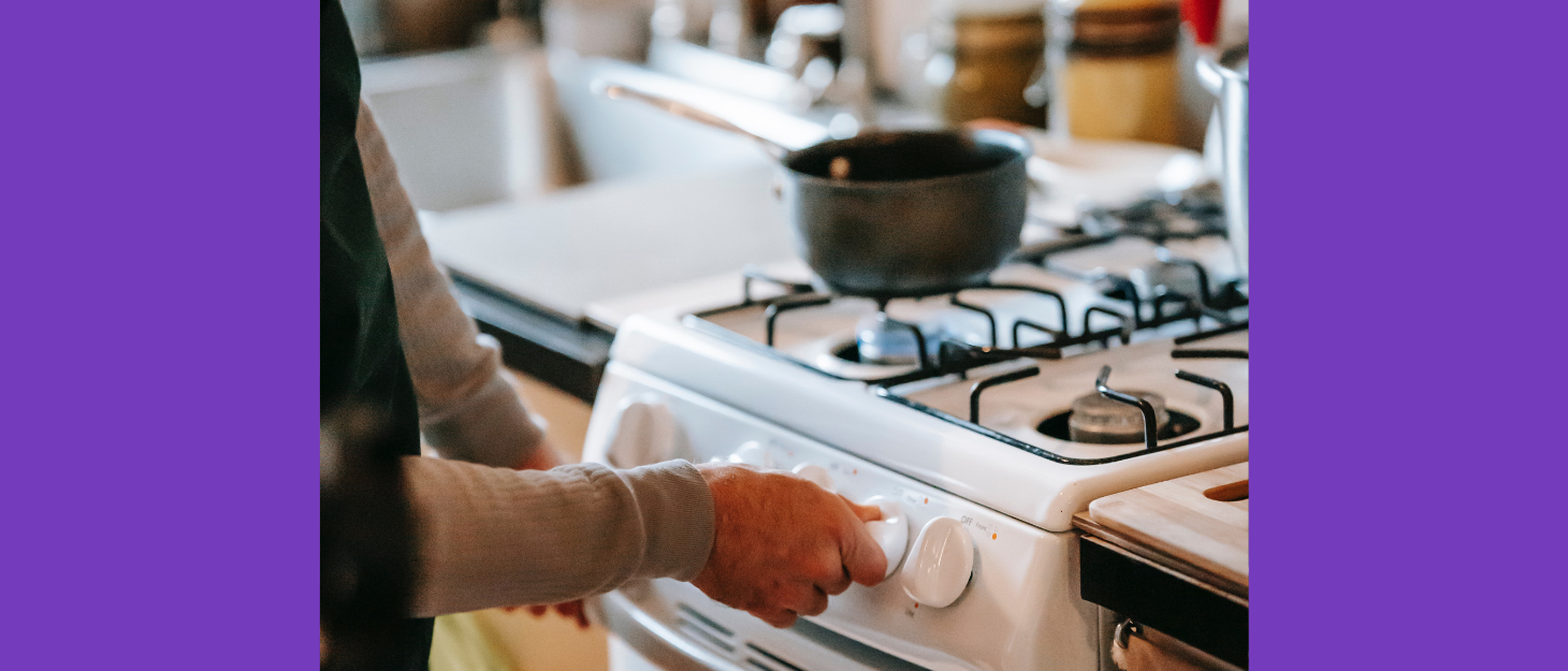 Woman turns on cooker to heat saucepan on hob