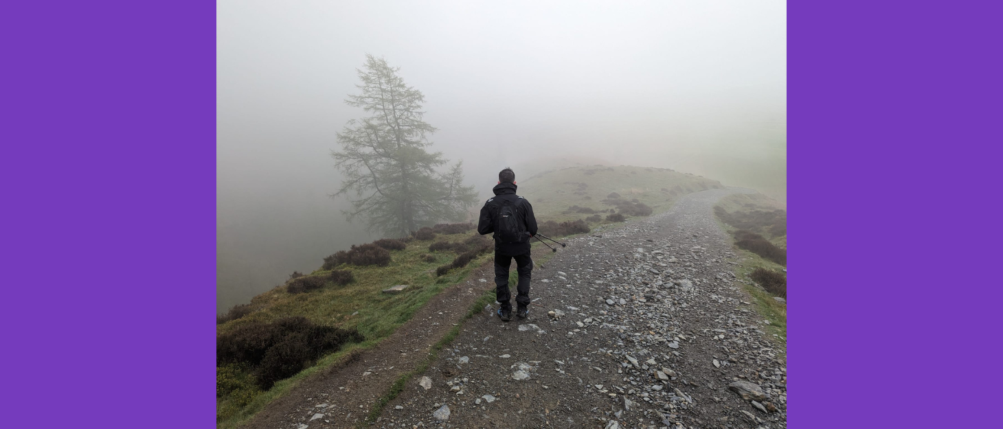 Man walking on a foggy mountainous path