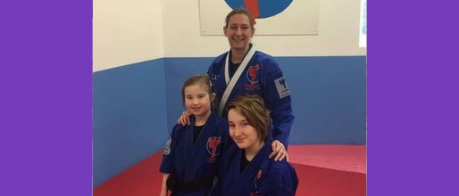 Mum and two daughters pose for a photo dressed in martial arts robes in gym