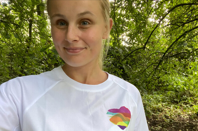 A woman in a woodland area taking a selfie wearing a white Family Fund t-shirt