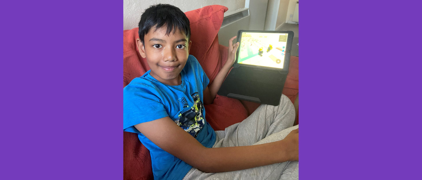 Ibrahim smiling as he holds his iPad on the sofa